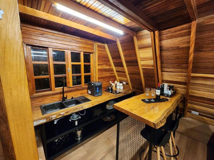 una cocina en una cabaña de madera con fregadero en Chalé - Romântico na Natureza, en Itapecerica da Serra