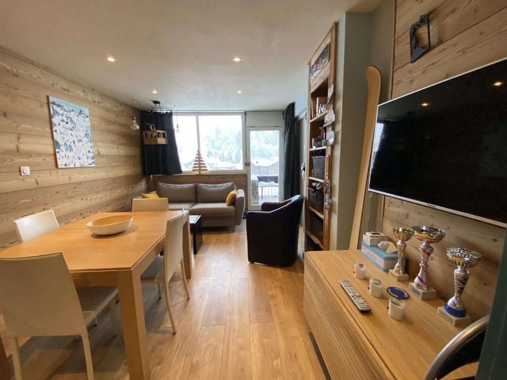un salon avec une table à manger et une télévision dans l'établissement Appartement cosy proche pistes et remontées avec balcon, accès wifi - FR-1-459-224, à La Clusaz