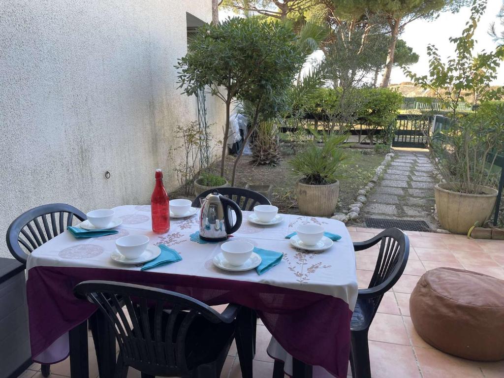 une table avec un chiffon de table violet sur une terrasse dans l'établissement Appartement RDC à Port Camargue - 6 Couchages, Accès Direct Plage, Parking, Jardin - FR-1-250-263, au Grau-du-Roi