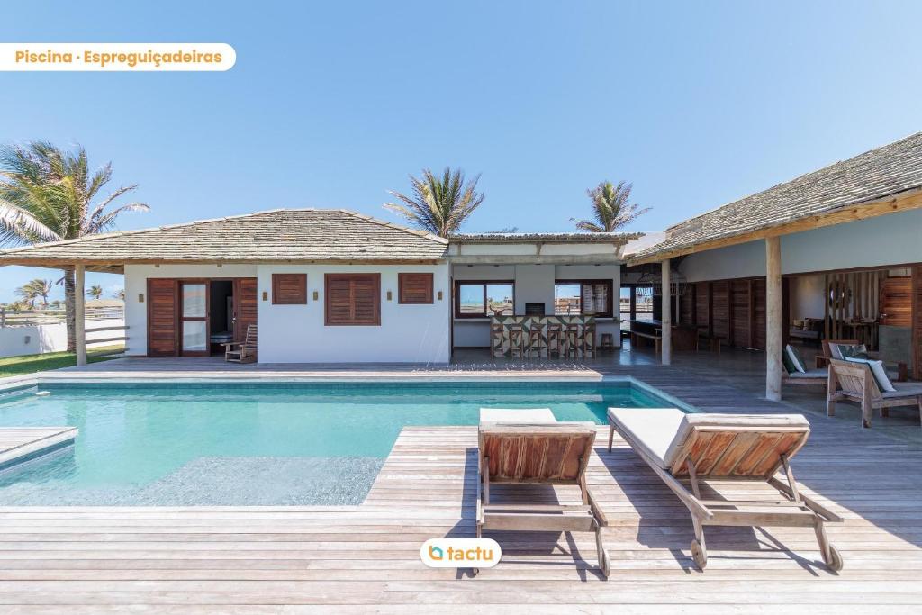 una piscina con 2 sillas y una casa en Vila Oásis Luxo Vista Mar Pontal do Maceió Fortim en Fortim