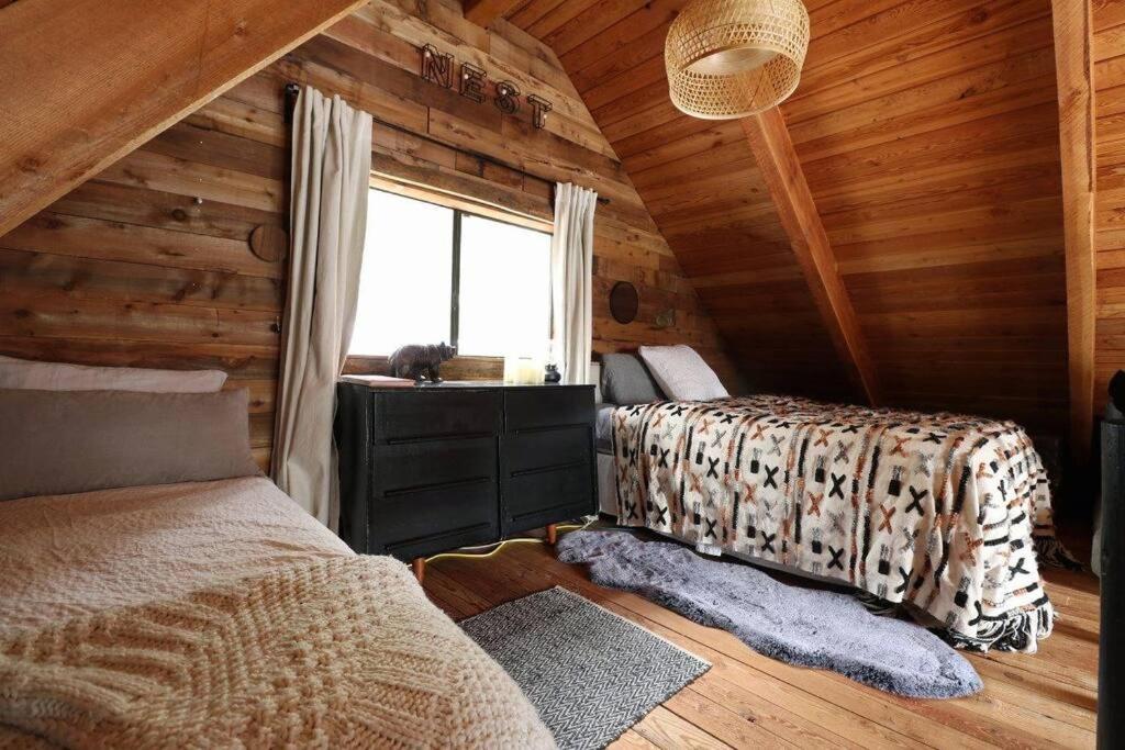 a bedroom in a log cabin with a bed and a window at Alpine Retreat: Off-Grid Cabin Winter Adventure in Pemberton