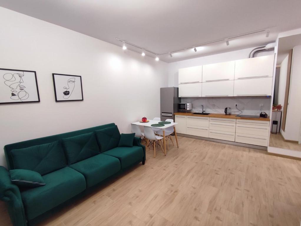 a living room with a green couch and a kitchen at Geodezyjna 72 Apartment in Warsaw