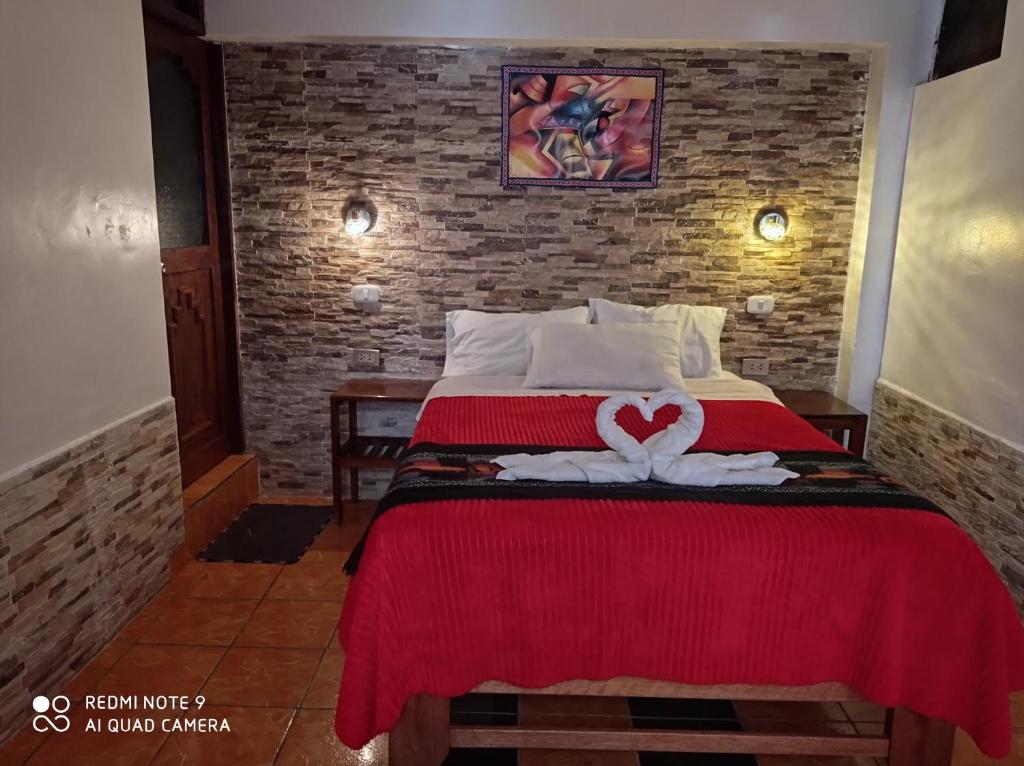 a hotel room with a bed with a red blanket at DENNY'S MAPI in Machu Picchu