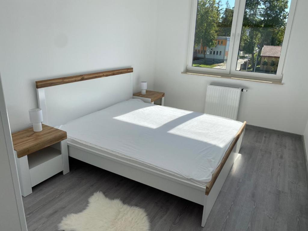 - une chambre blanche avec un lit et une fenêtre dans l'établissement Apartament 33 Nad Iławką, à Iława