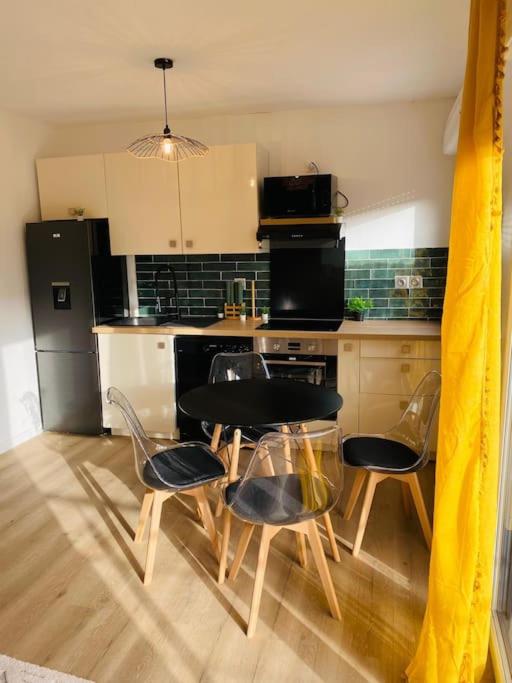 a kitchen with a table and chairs in a kitchen at Appartement standing Le Havre in Le Havre