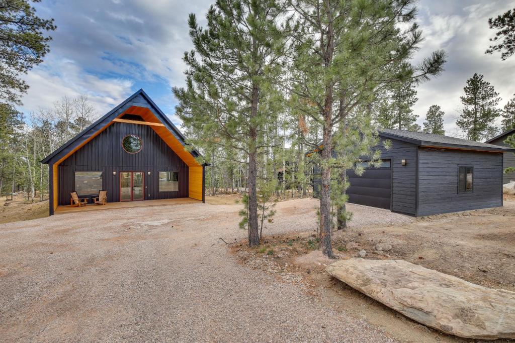 a black and orange house in the woods at Family-Friendly Lead Cabin with Loft and Balcony! in Lead