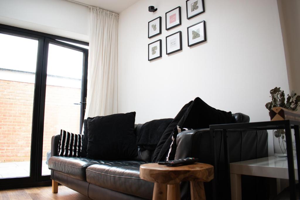 a living room with a leather couch and a table at SW Stay - Stylish One Bedroom with patio in London