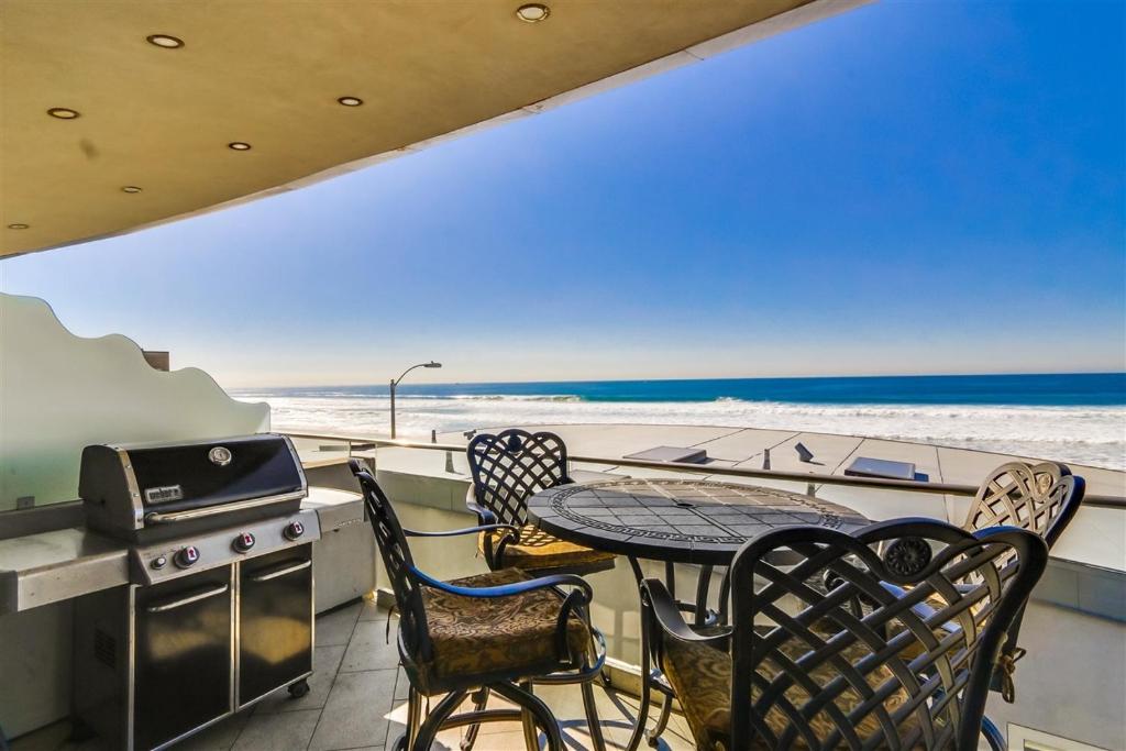 Ocean view, two-level condo with stunning view, decks, fast WiFi & fireplace في سان دييغو: شرفة مع طاولة وكراسي والشاطئ