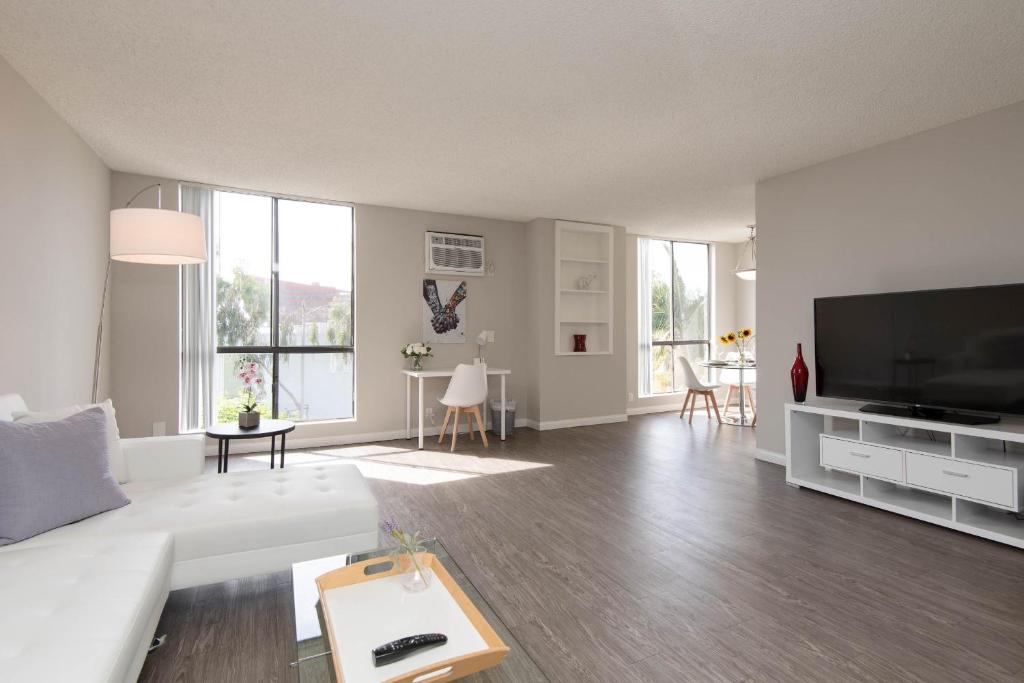 een woonkamer met een witte bank en een flatscreen-tv bij Prime Location 1-Bedroom with Pool in Los Angeles