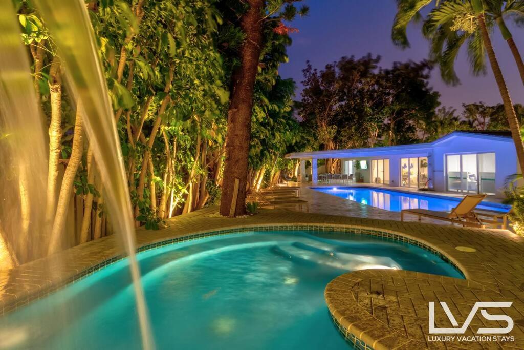 a swimming pool in front of a house at Cascada-Luxe Resort Heated Pool HotTub Wlk 2 Beach in Fort Lauderdale