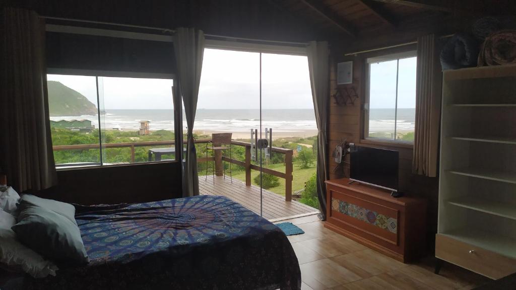 um quarto com uma cama e vista para o oceano em Koa Cabana praia do luz em Imbituba