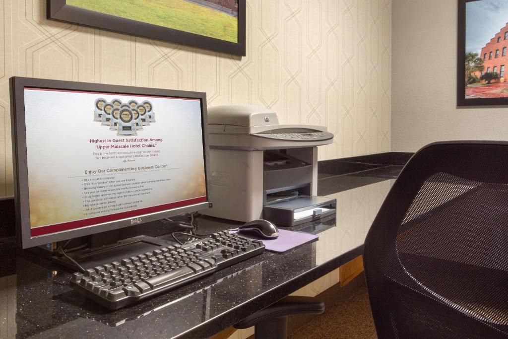 a desk with a computer monitor and a keyboard at Drury Inn & Suites Lafayette LA in Lafayette
