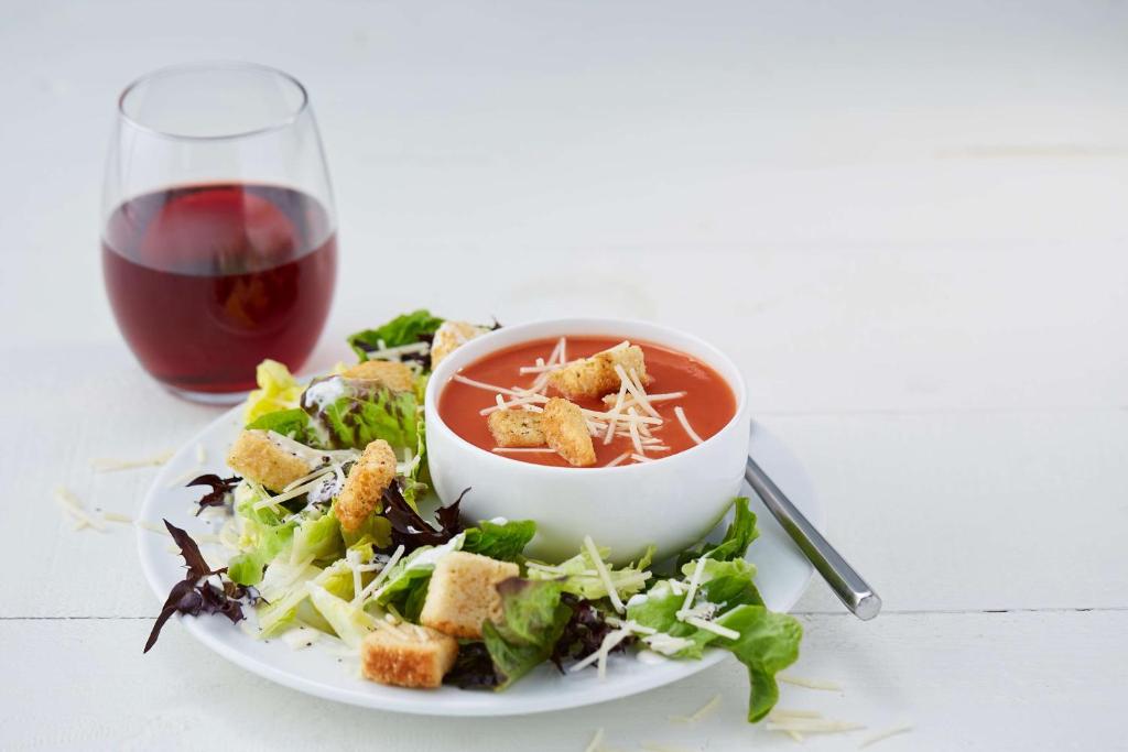 a plate of salad with a bowl of soup and a glass of wine at Drury Inn & Suites Lafayette LA in Lafayette