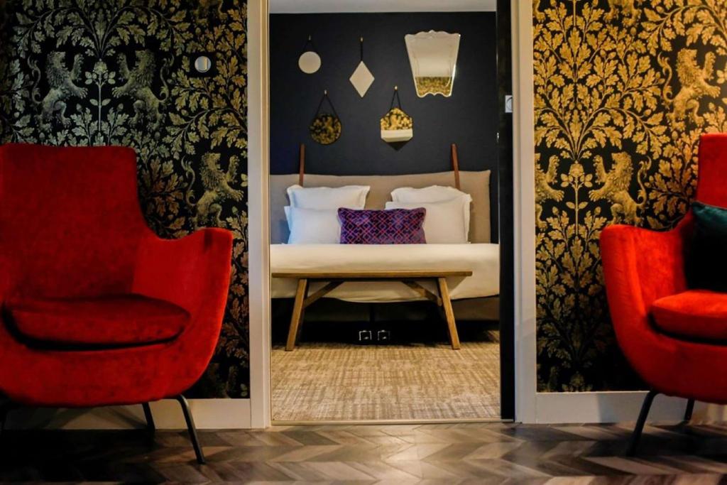 a bedroom with two red chairs and a bed at Best Western Plus Le Conquerant Rouen Nord in Bois-Guillaume