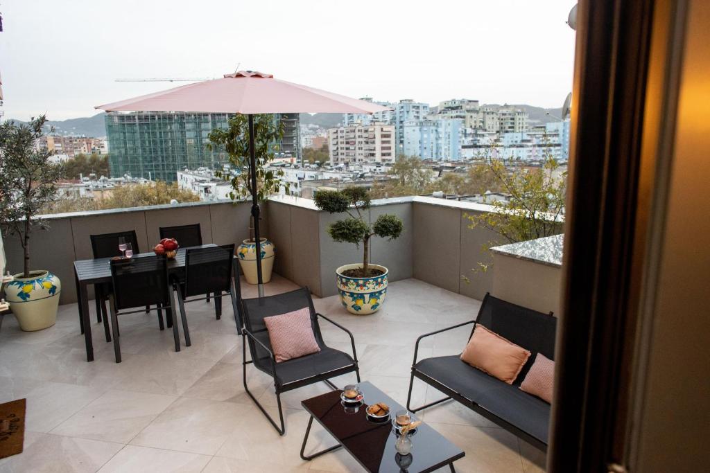 balkon ze stołem, krzesłami i parasolem w obiekcie Terra'Vista Apartments w Tiranie