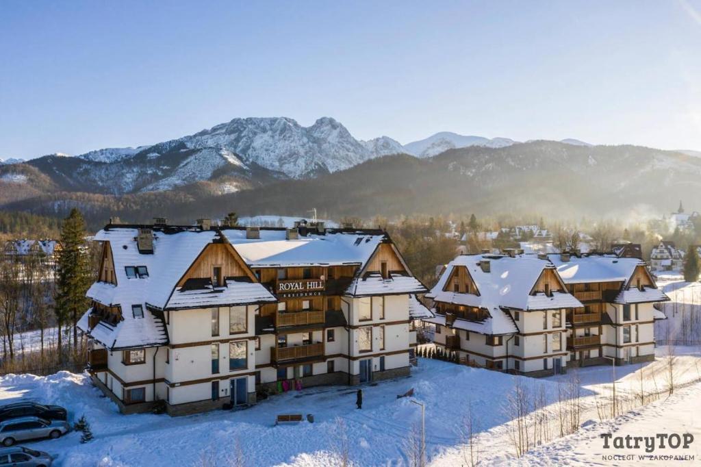 un grupo de edificios en la nieve con montañas en el fondo en Royal Hill Residence, en Zakopane