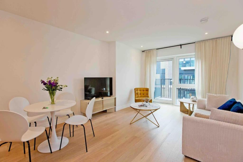 uma sala de estar com um sofá, uma mesa e uma televisão em Westwood Brand new AC Luxury 2bed 2 bathrooms spacious family unit em Londres