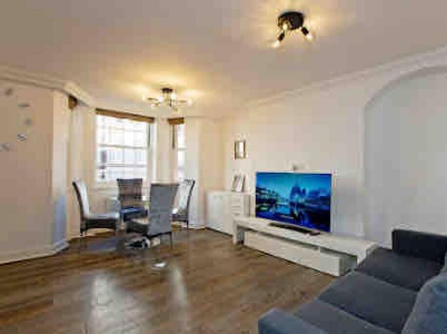 ein Wohnzimmer mit einem Sofa und einem Flachbild-TV in der Unterkunft Fitzrovia 2 Bed modern +Lift central London in London