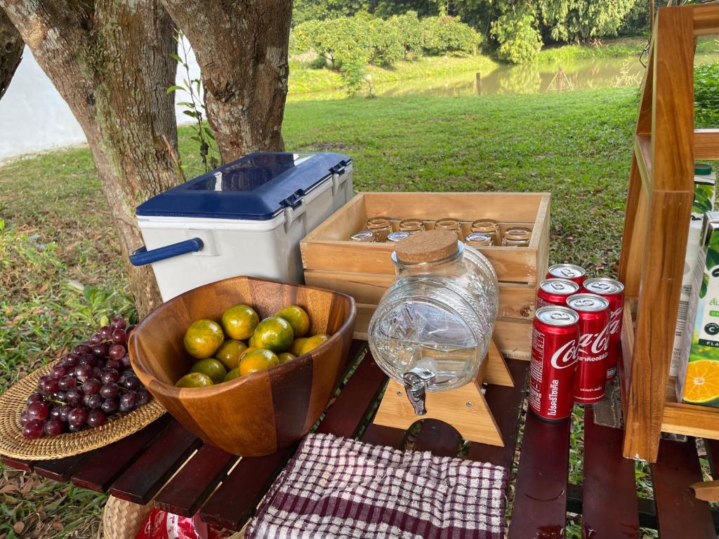 a picnic table with a basket of apples and soda cans at Punpawn ปั๋นปอนด์ Farm Stay in Chiang Saen