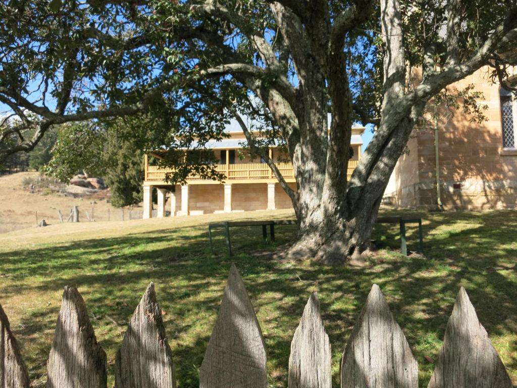 a fence in front of a tree and a building at Hartley Historic Cottages in Hartley