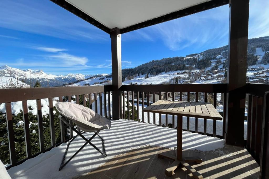 uma cadeira numa varanda com vista para as montanhas em Bright apartment - close to the slopes em Demi-Quartier