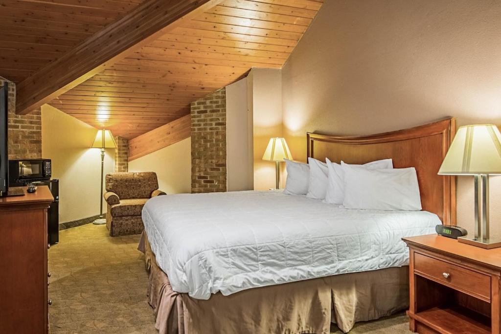 um quarto de hotel com uma cama e uma cadeira em Royal Inn Suites em Huntington
