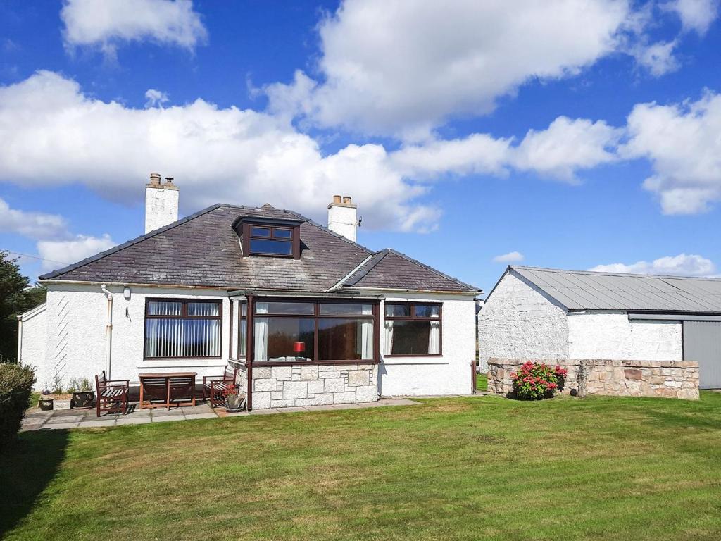 a white house with a lawn in front of it at Auld House in Brora