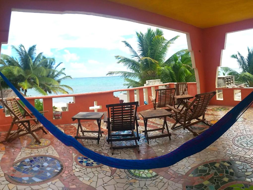 El Placer的住宿－Mayan Beach Garden，一个带椅子和吊床的门廊和大海