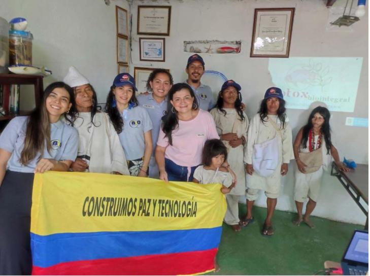 un groupe de personnes posant pour une photo avec un drapeau dans l'établissement Glamping Bio Coliving Tayrona, à Santa Marta