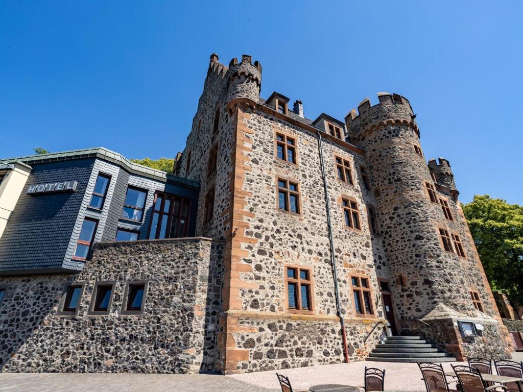 ein Gebäude mit Türmchen und Stühlen davor in der Unterkunft Hotel Burg Staufenberg in Staufenberg