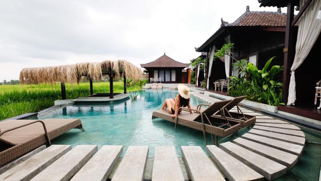 a woman sitting on a raft in a swimming pool at Kayangan Villa Ubud in Tegalalang