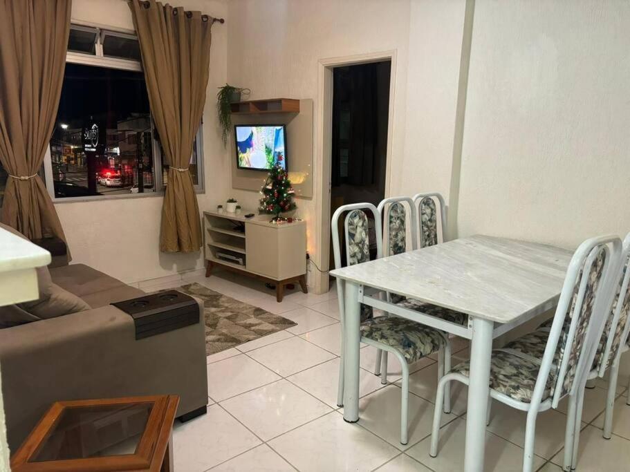 uma sala de estar com uma mesa e cadeiras e uma televisão em Apartamento 108 Centro Caragua em Caraguatatuba