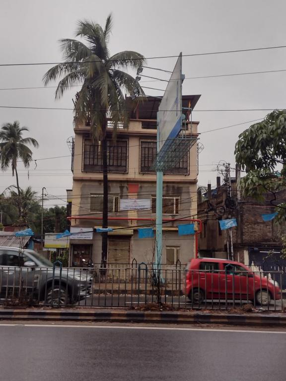Gauripur的住宿－Hotel Skyking，一座棕榈树的建筑,前面有一辆红色的汽车