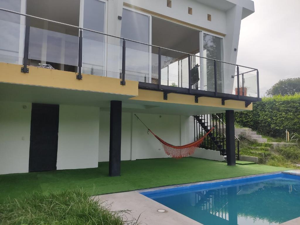 een huis met een hangmat naast een zwembad bij Finca de descanso y diversión in Tocaima