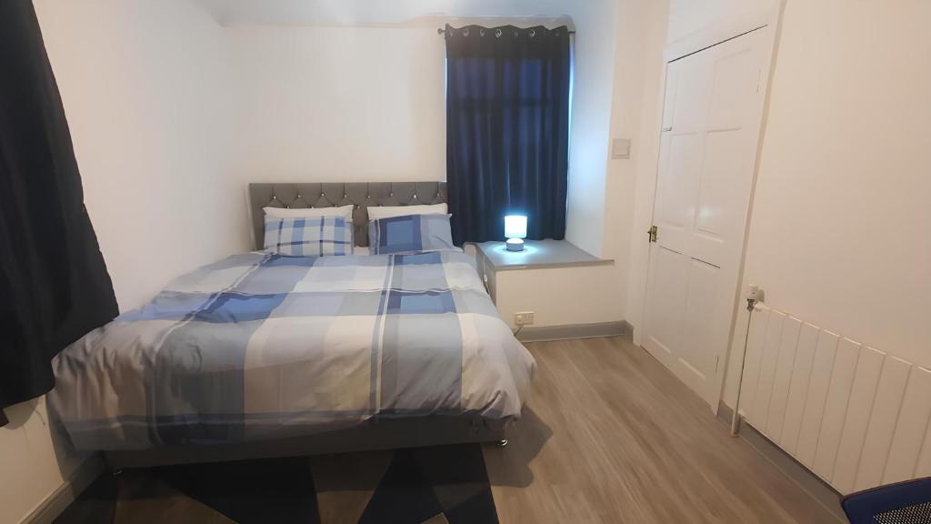 a bedroom with a bed with blue pillows and a window at Boutique Bliss with Super king size bed in Killingbeck
