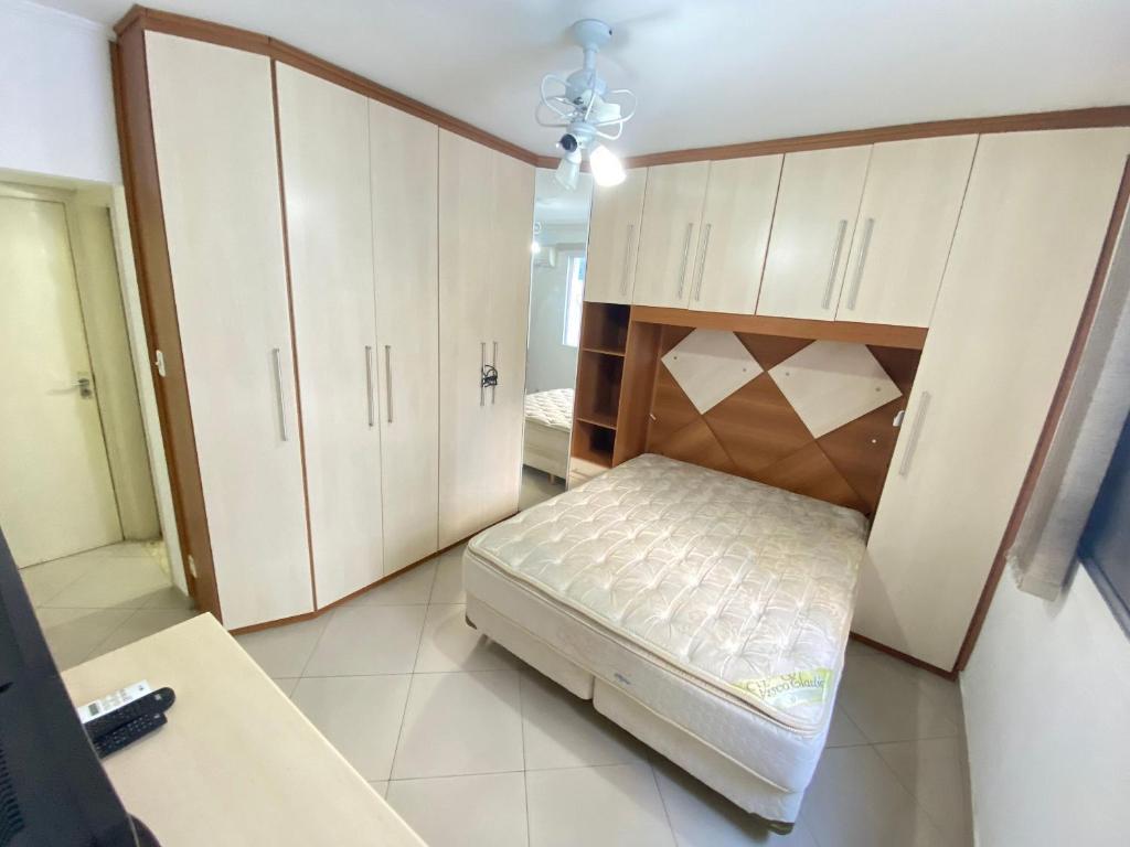 1 dormitorio con 1 cama en una habitación con armarios en Pé na areia canto do forte II, en Praia Grande