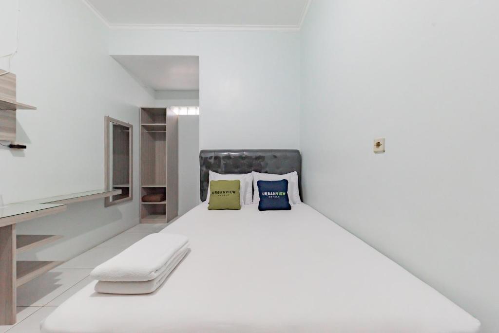 a white bed with two pillows on it in a room at Urbanview Hotel Sunday Cirebon by RedDoorz in Cirebon