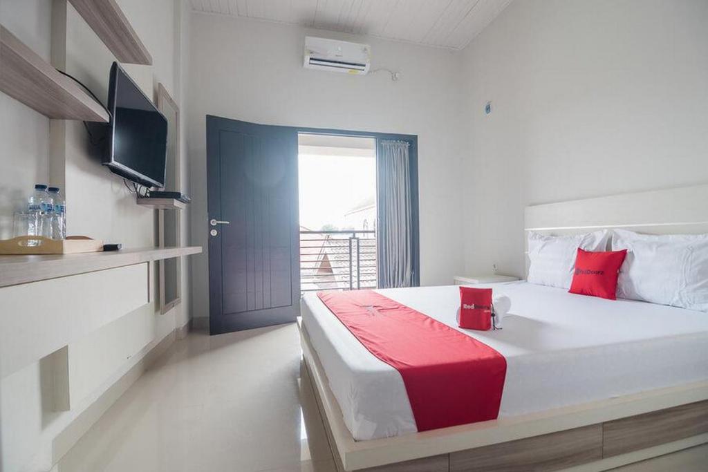 een slaapkamer met een groot bed en een rode deken bij RedDoorz Syariah near Tugu Juang Jambi in Jambi