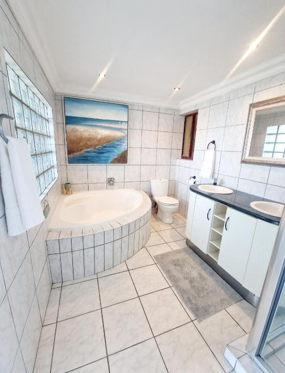 a bathroom with a tub and a toilet and a sink at Ripple In Time- Gorgeous Views- Tennis- BBQ in Umdloti