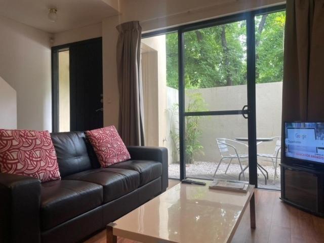 a living room with a leather couch and a table at RNR Serviced Apartments Adelaide - Sturt St in Adelaide