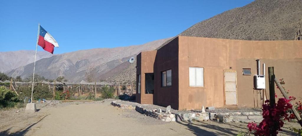 a building with a flag in front of a mountain at DIAGUITAS, VICUÑA, VALLE DEL ELQUI in Diaguita