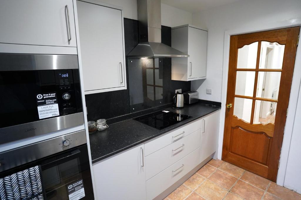 a kitchen with white cabinets and black counter tops at Comber Cozy Home in Comber