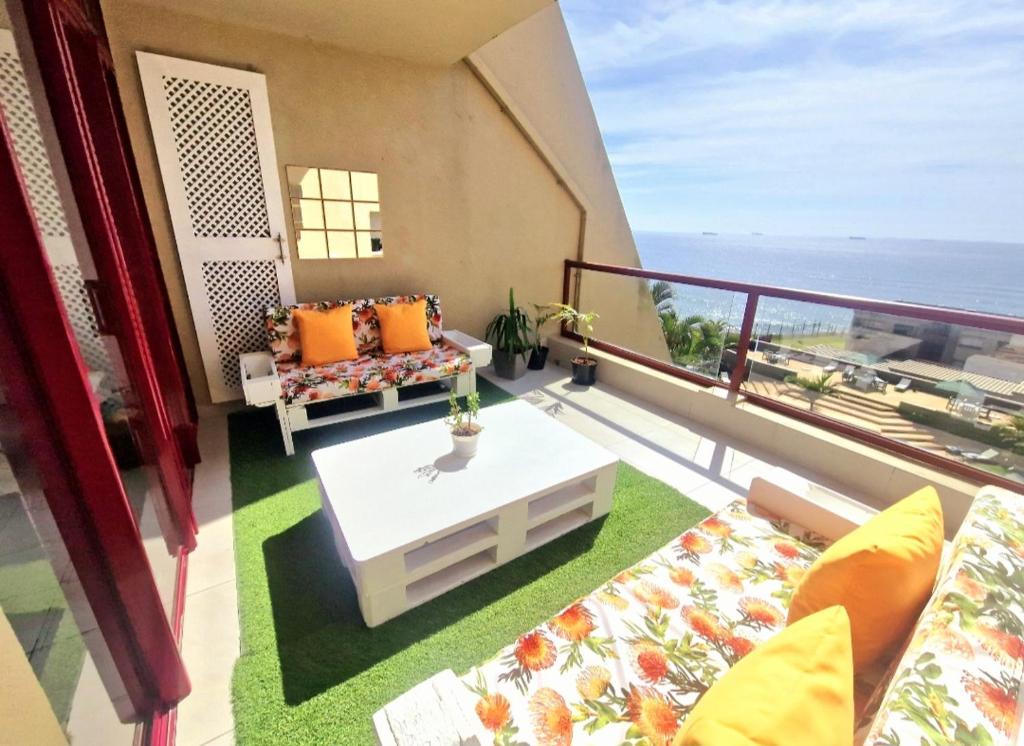 een balkon met een bank en een salontafel bij Ripple In Time- Pool- Tennis- Braai- Aircon in Umdloti