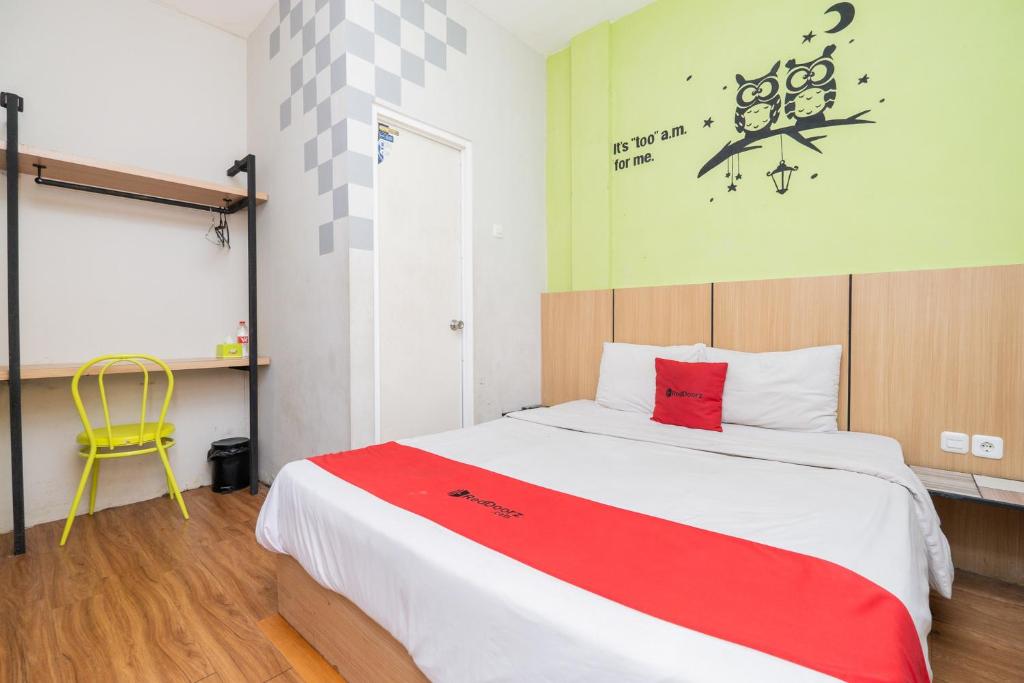 a bedroom with a large bed with a red blanket at RedDoorz @ Darmo Surabaya in Dinojo