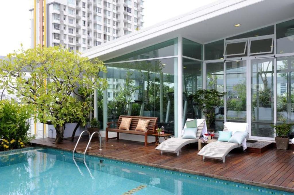 a house with a swimming pool next to a building at Sabai Sathorn Service Apartment in Bangkok