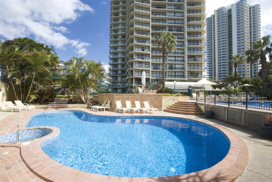 a swimming pool with chairs and a large building at Core beachfront 2 Bedrooms Apartment by Gold Coast Premium in Gold Coast