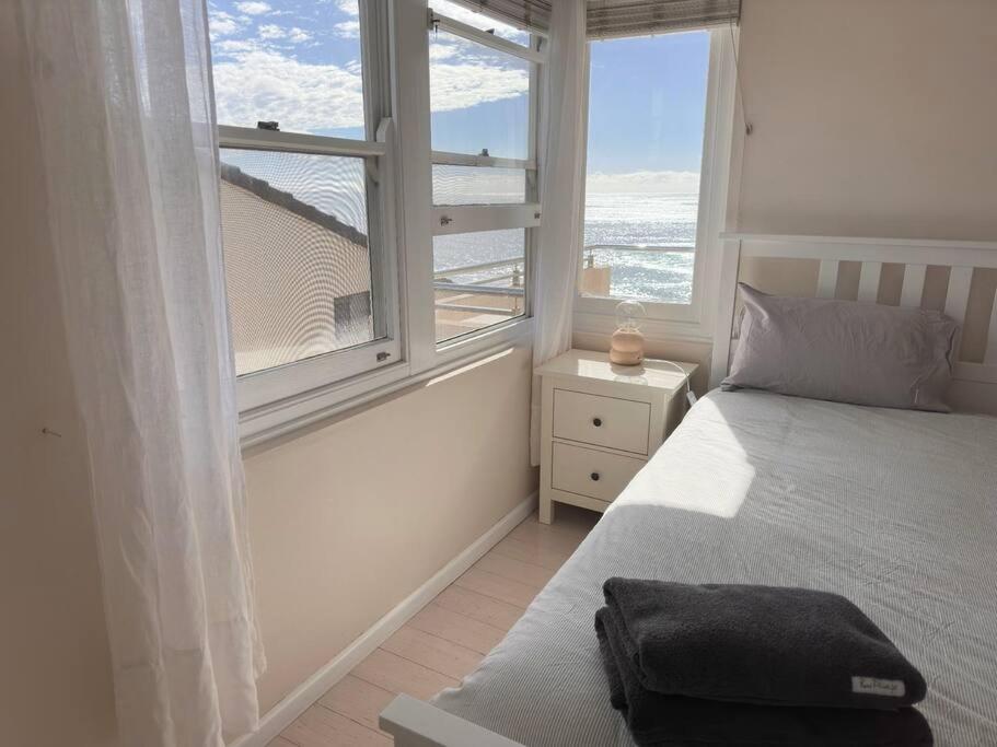 een slaapkamer met een bed en een groot raam bij Sunny Apt on The Esplanade - Aircon in Cronulla