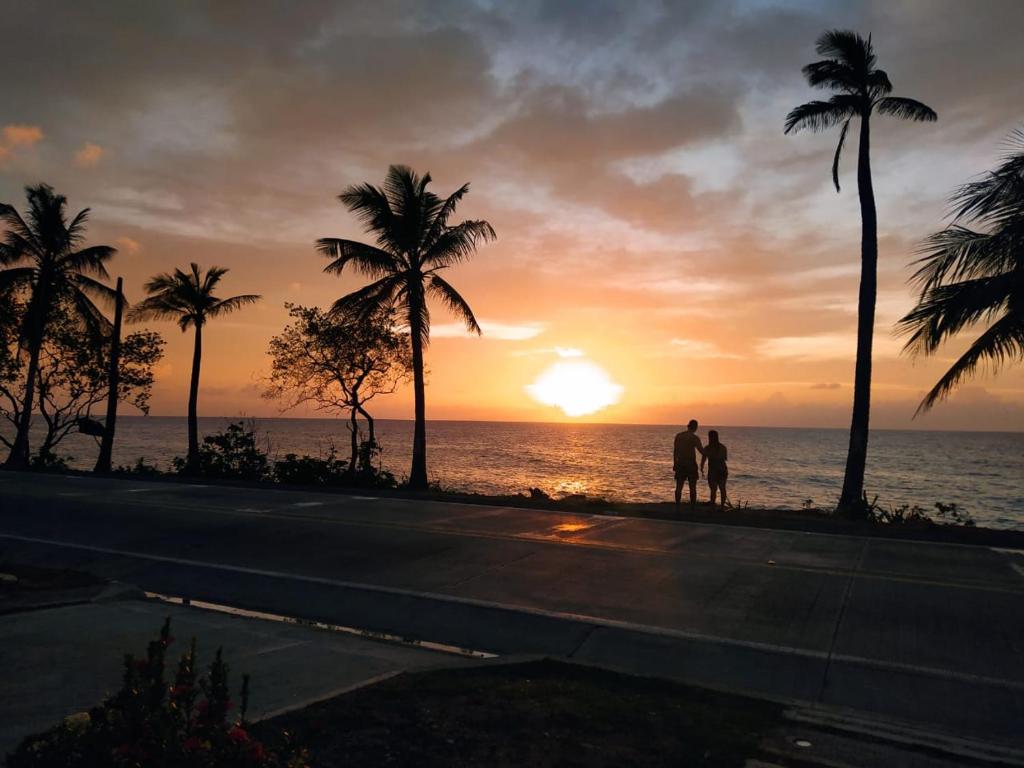 dos personas de pie en una acera viendo la puesta de sol en Alojamiento turístico Keniant's en San Andrés