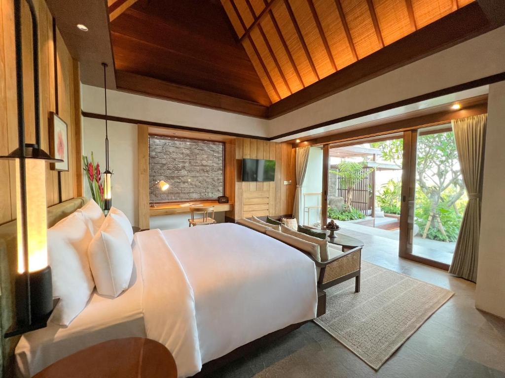a bedroom with a large bed and a large window at The Ridge Bali in Ubud