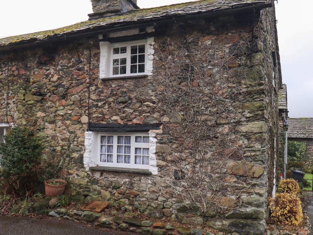 an old stone house with a white window at How Head Cottage in Ambleside